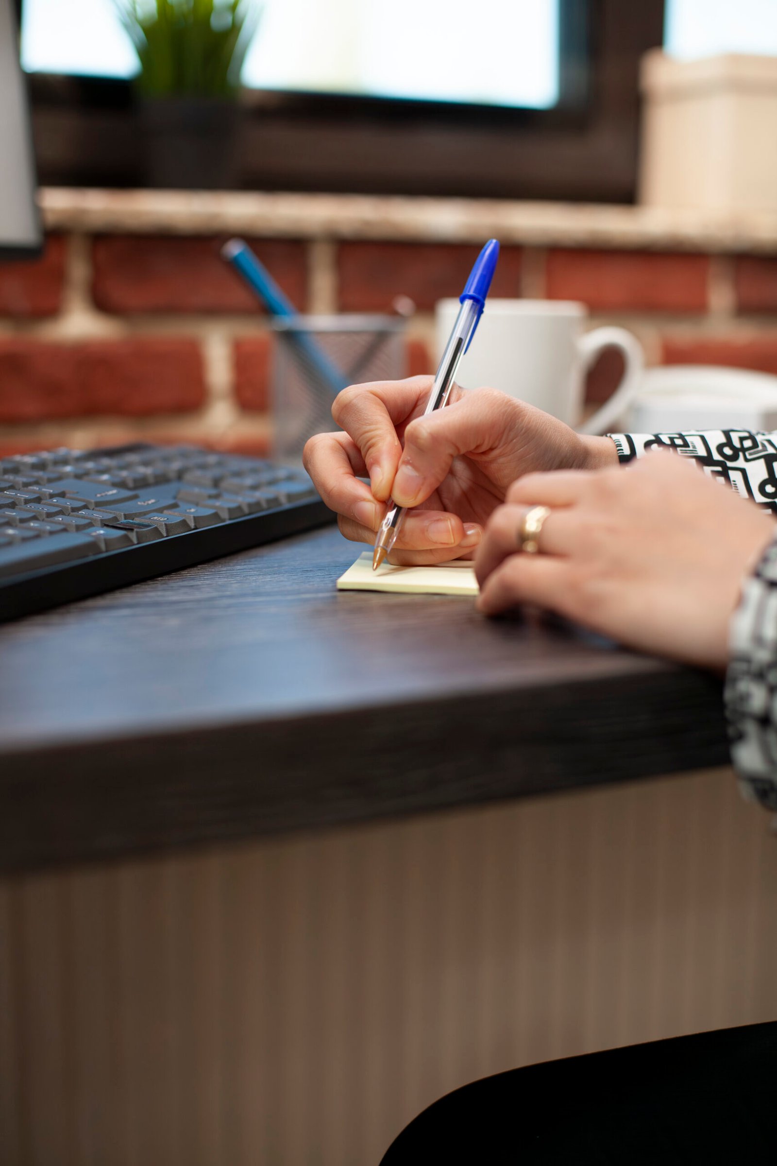 person writing on sticky note on desk